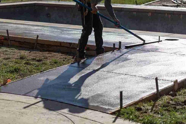 Concrete driveway installation with a worker smoothing freshly poured surface using a finishing tool in Columbia Station, OH