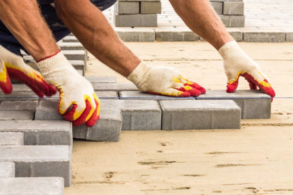 Contractor installing concrete pavers for patio construction on a leveled sand base in Columbia Station, OH