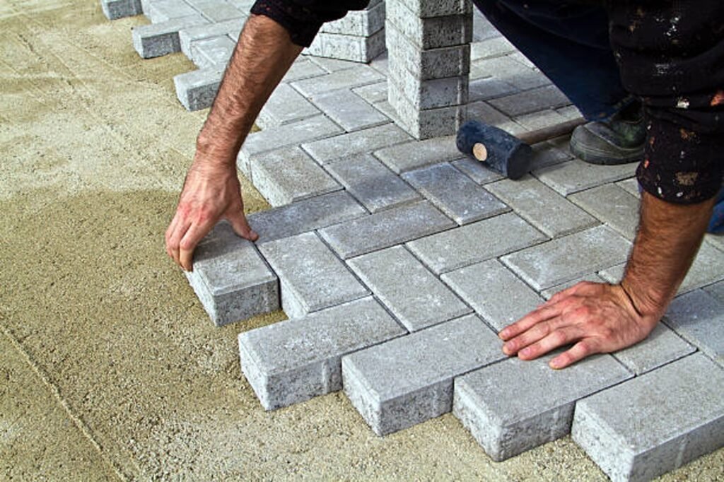 Contractor installing concrete pavers for patio construction on a compacted base in Columbia Station, OH