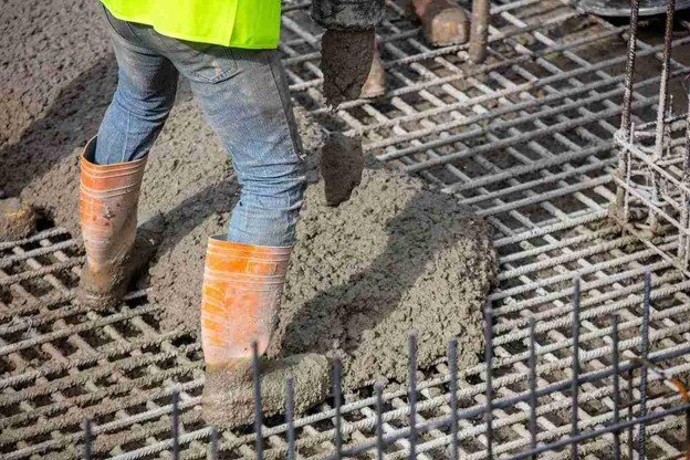 Worker pouring fresh concrete over steel rebar grid for structural slab construction in Columbia Station, OH